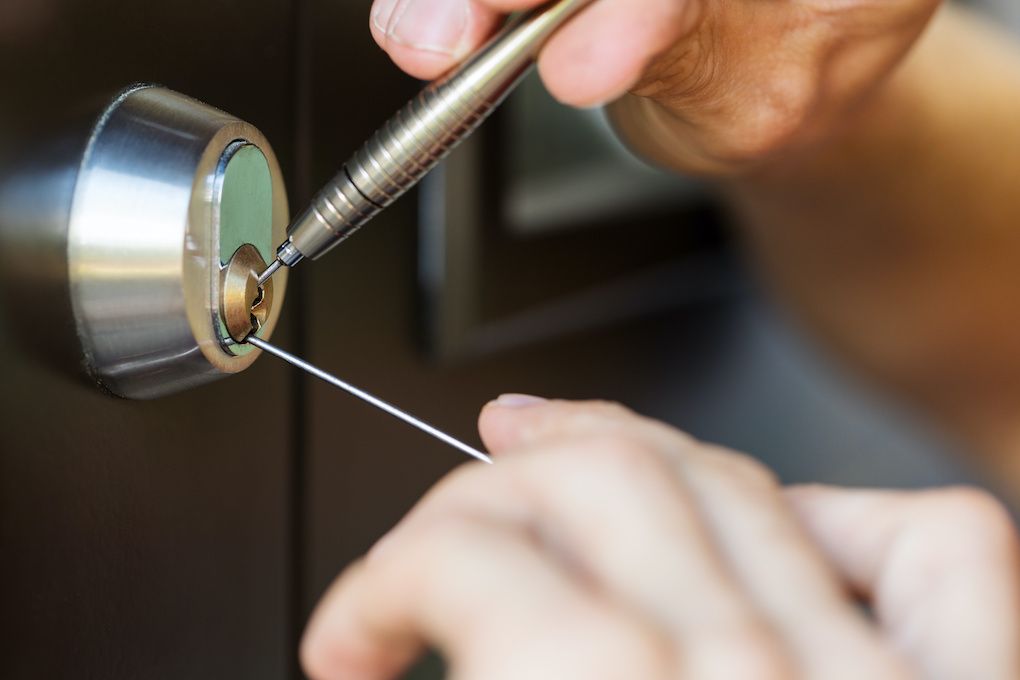 Locksmith picking a deadbolt lock to open a locked door